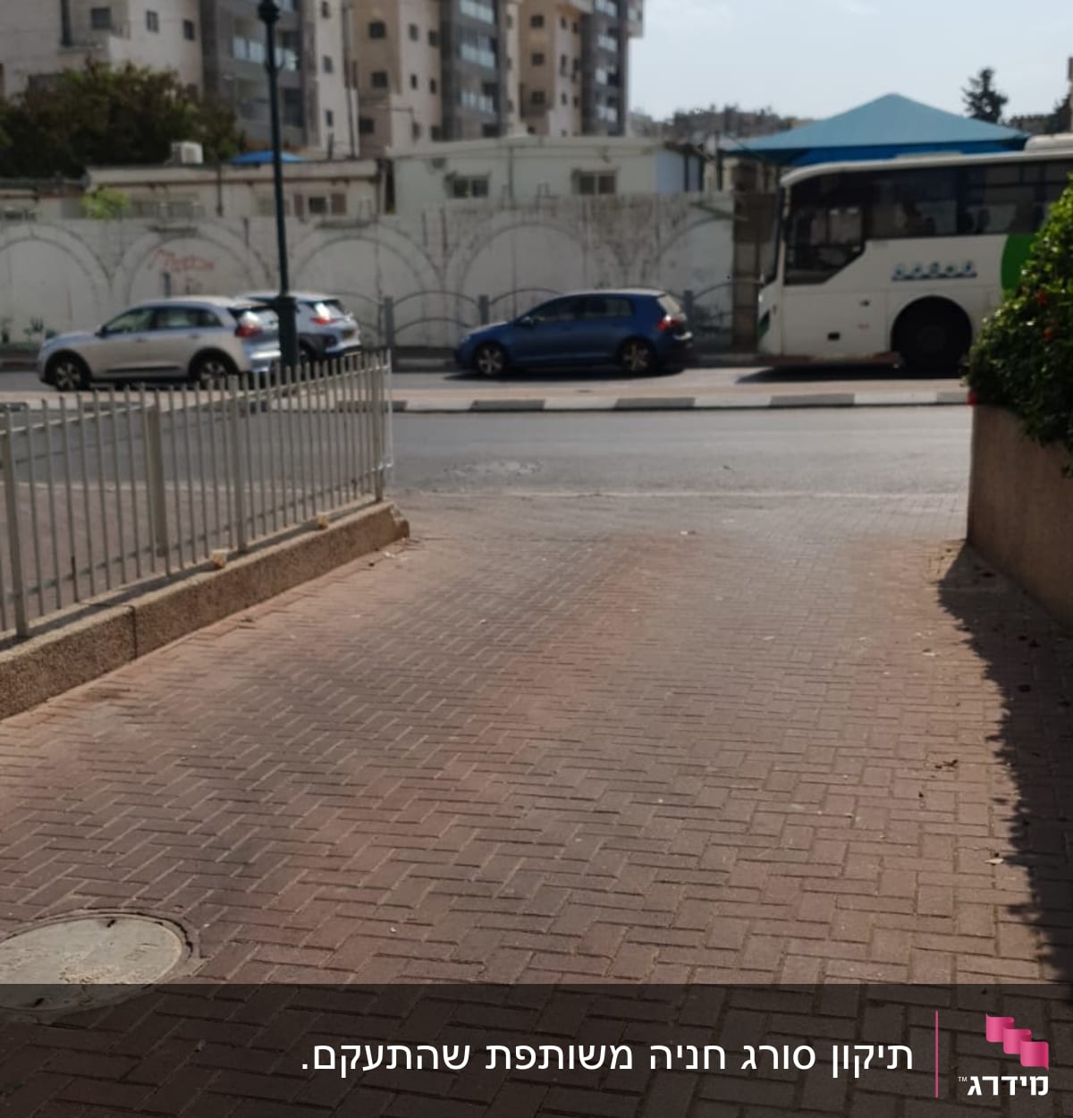 גדר מתכת לצד מדרכה מרוצפת בלבנים אדומות